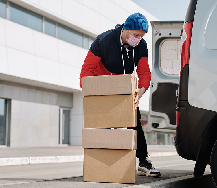 Masked employee of DTS Logistics holding packages safely