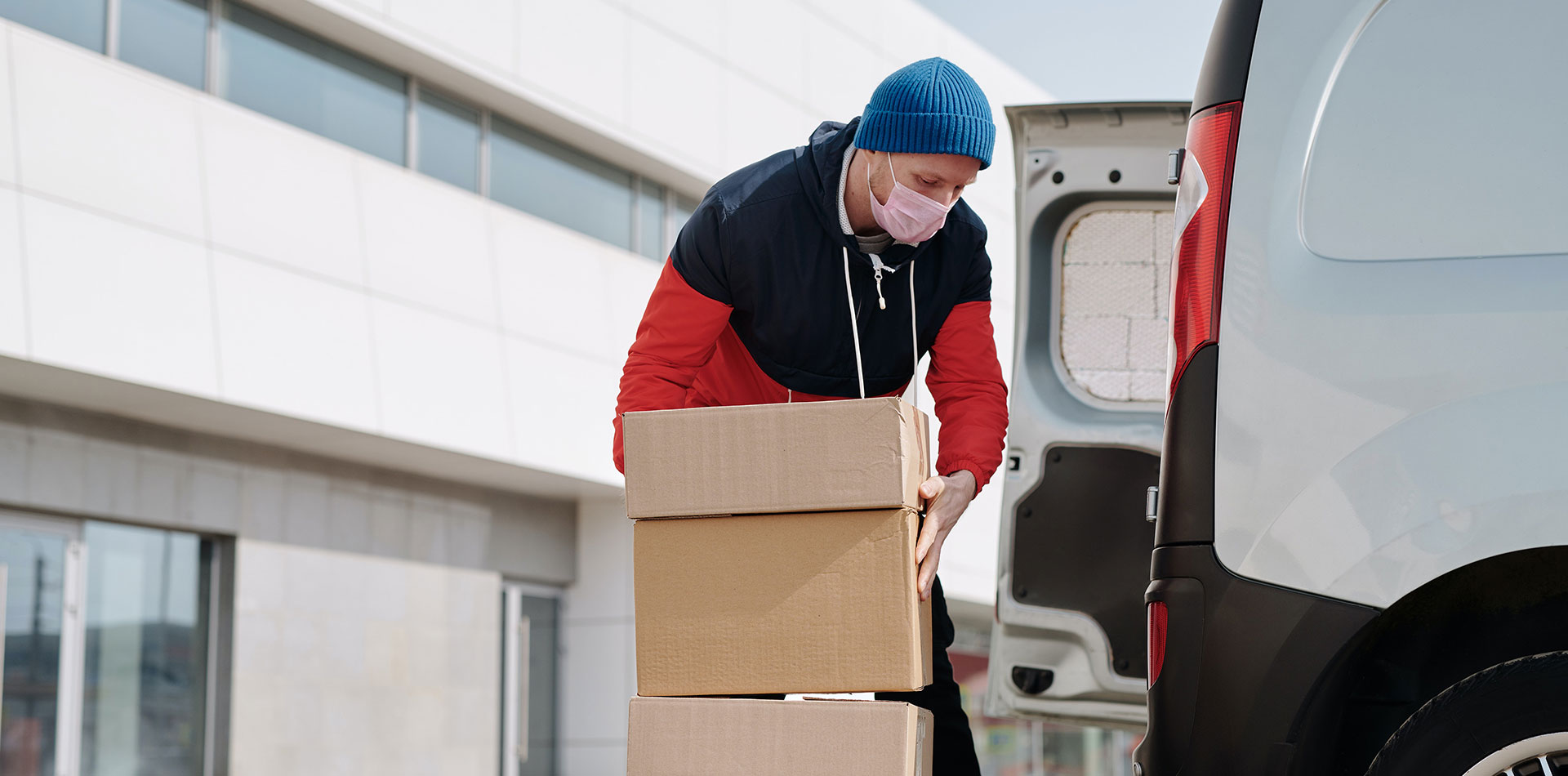 Masked employee of DTS Logistics holding packages safely